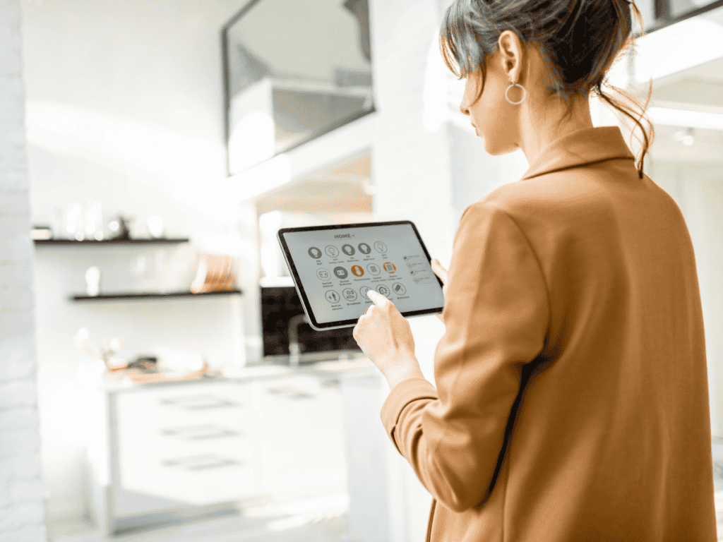 Person using a tablet to control smart home devices in a modern kitchen setting.