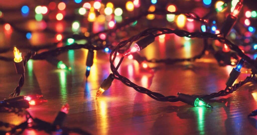 A close-up of colorful string lights—red, green, blue, and yellow—decking the halls as they elegantly spread out across a wooden surface.