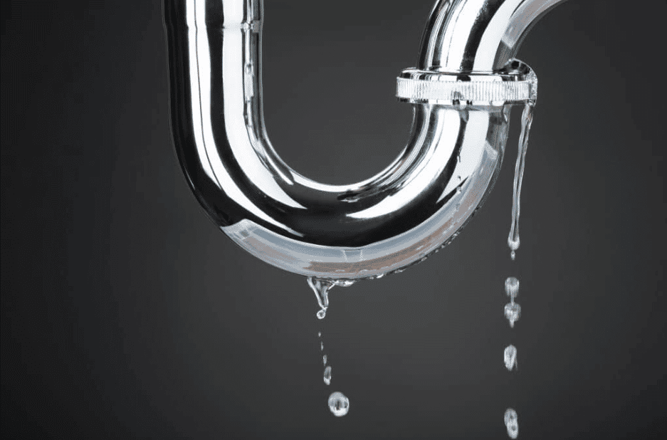 Close-up of a leaking metallic pipe with water droplets falling against a dark background.