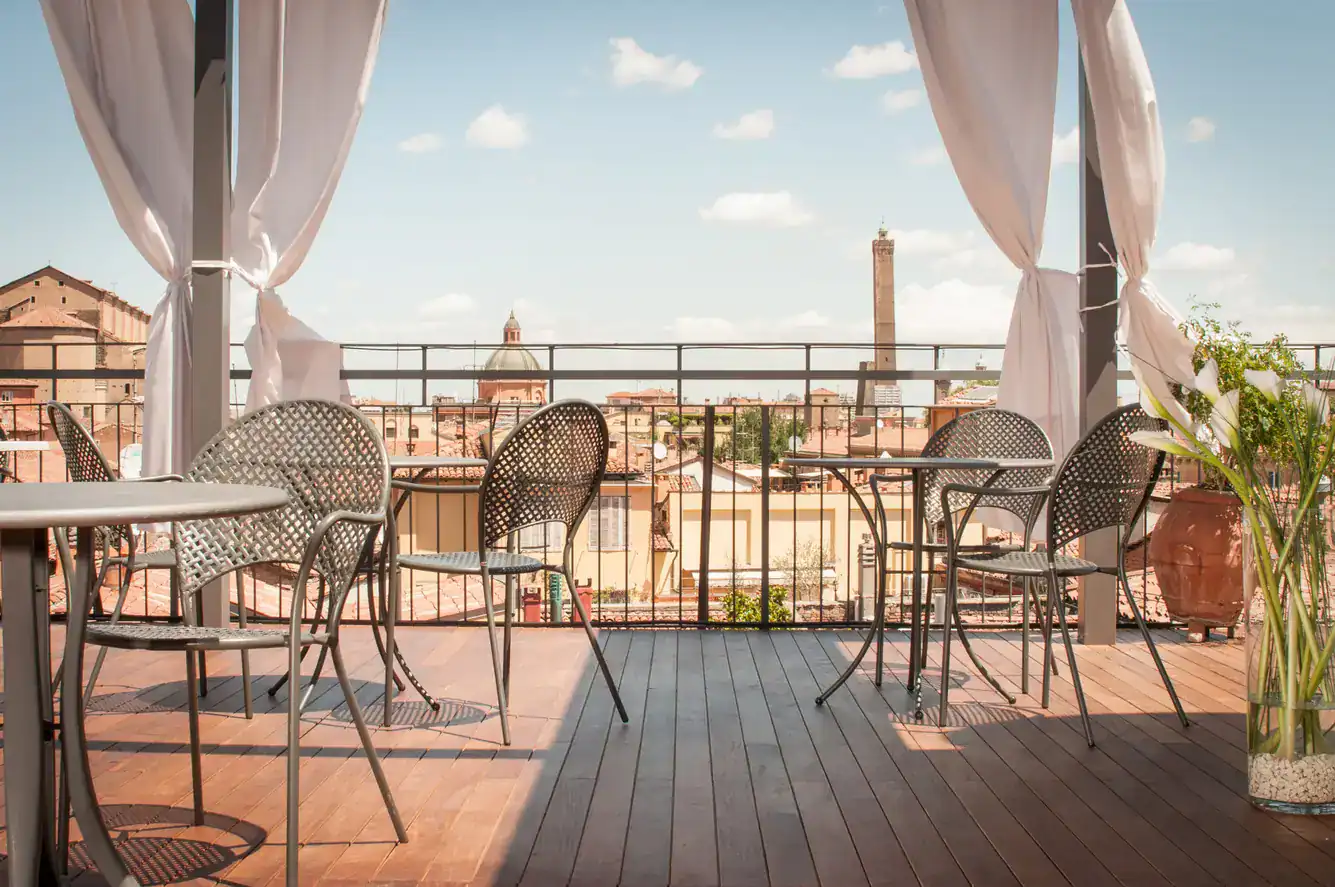 Balcone con tavoli e sedie per colazioni e relax all'aperto con vista sulle due Torri di Bologna