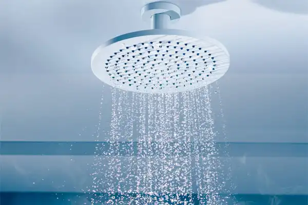 Overhead showerhead with water spraying downward, showcasing ideal water pressure against a tranquil blue background.