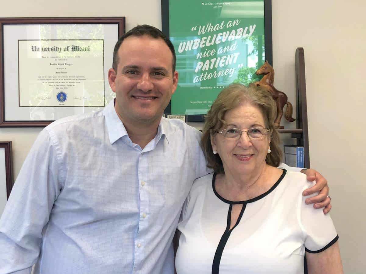 Justin Ziegler, personal injury lawyer, smiling with a happy former client at his Coral Gables office.