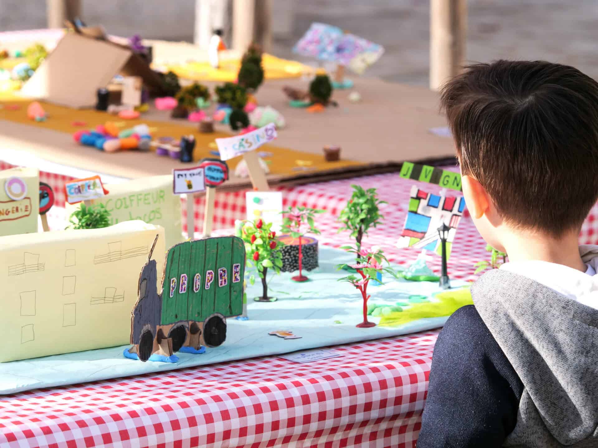 Un enfant observe une maquette du quartier des Constellations à Juvignac 