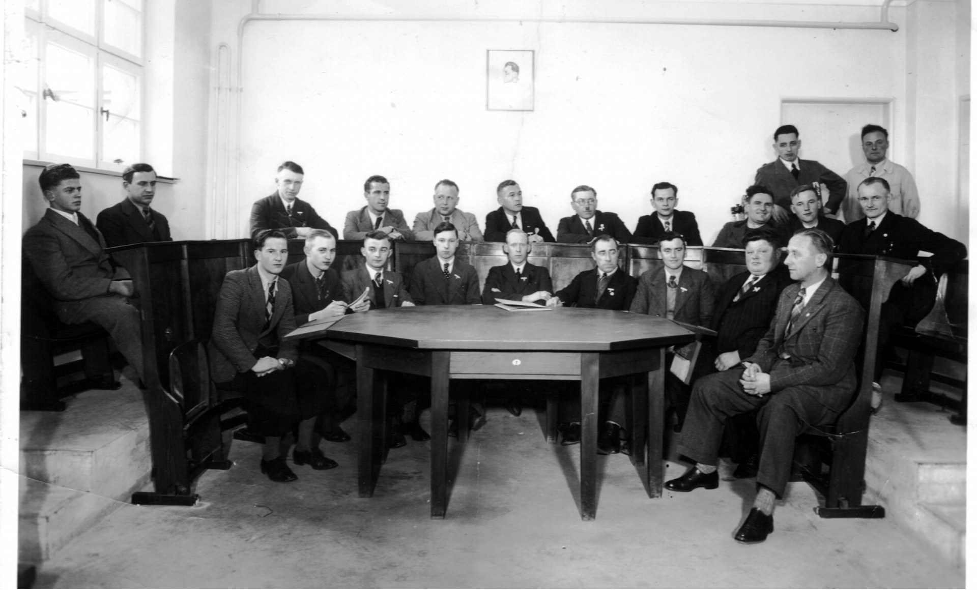 Schulklasse mit Lehrern und Schülern in einem alten Klassenzimmer.