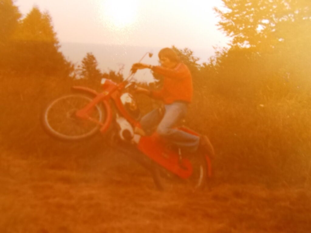 Motorrad im Sprung auf unebenem Gelände bei Sonnenuntergang.
