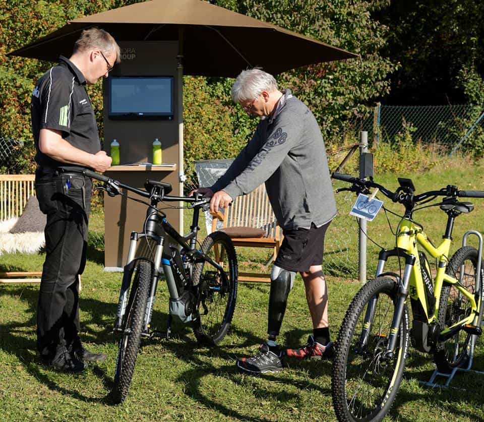 Zwei Männer beim Fahrradservice im Garten, eines repariert, das andere beobachtet.