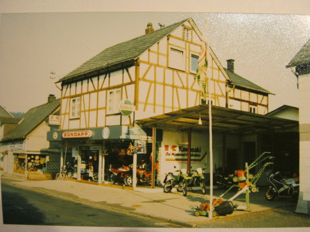 Historisches Fachwerkhaus mit Geschäft und Motorrädern vor dem Laden.