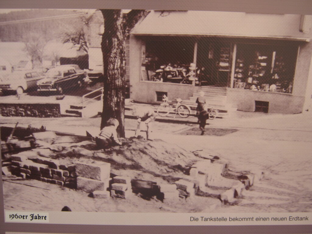 Altes Foto aus den 1960er Jahren mit Straßenszene und Tankstelle.