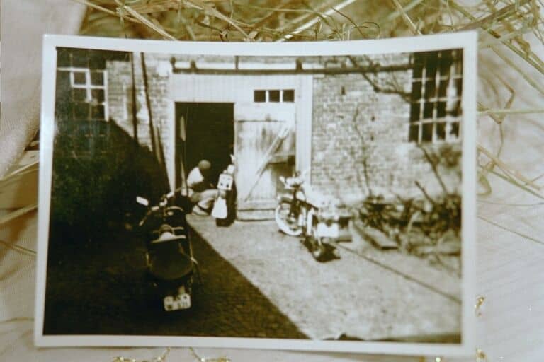 Altes Schwarz-Weiß-Foto von Kindern vor einem Haus mit Fahrrädern.