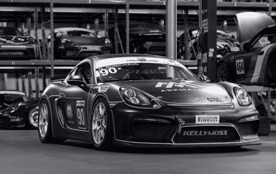 Kellymoss racing Porsche 911 in a garage with other cars.