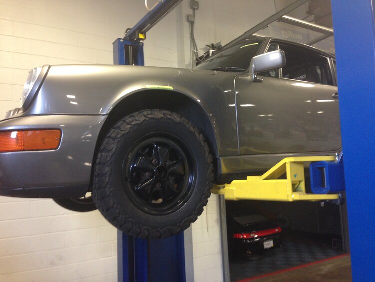 1990 Porsche 964 C4 on a hydraulic lift in a garage.