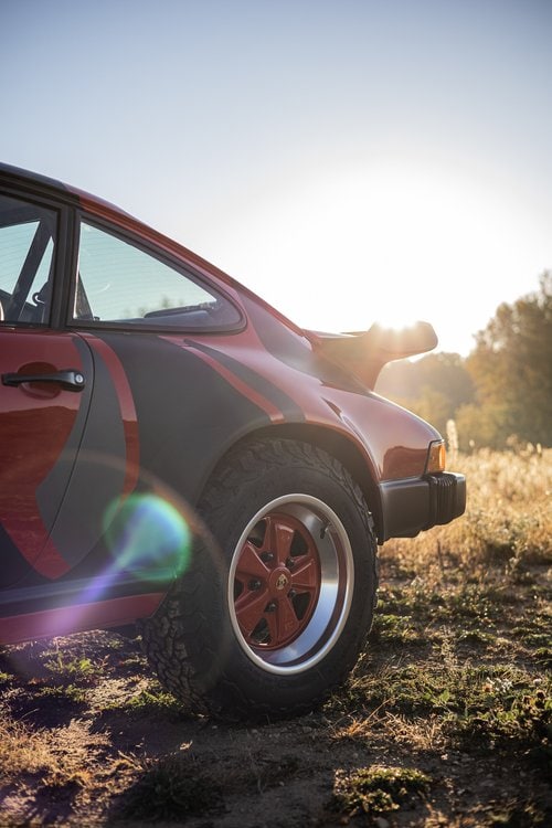 Vintage Porsche 911 with rally-inspired design in a natural setting.