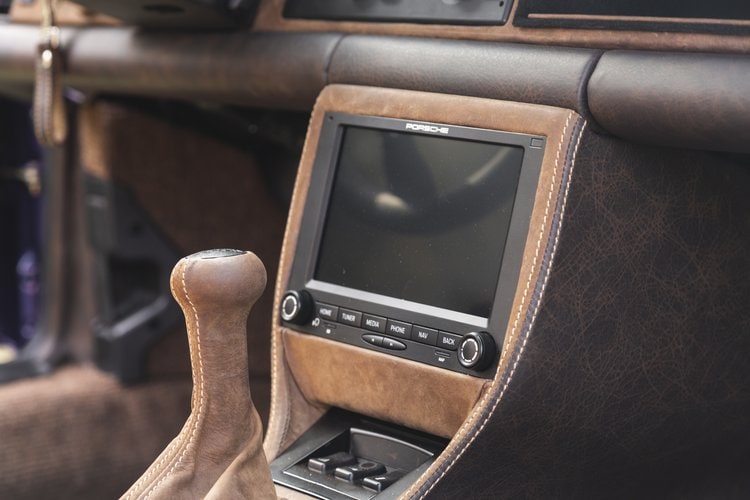 Vintage car interior with a modern touchscreen display and manual gear shift.