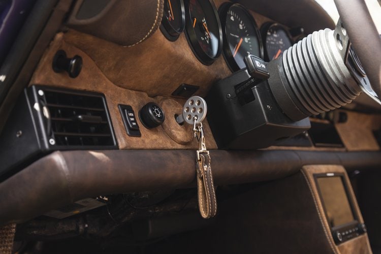 Close-up of Porsche 964 C4 interior dashboard with key and steering wheel.