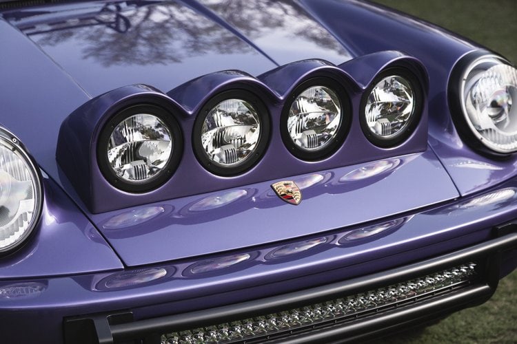 Close-up of a vintage Porsche 964 C4 with custom headlight covers and purple paint.