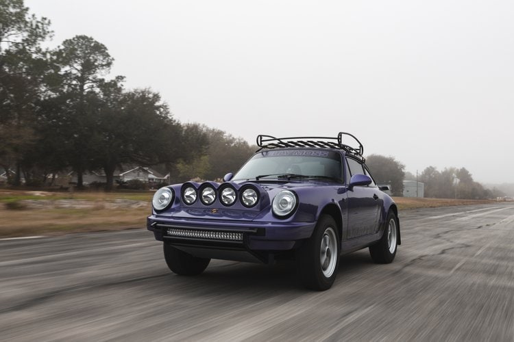 Purple 1991 Porsche 964 C4 with off-road lights on a foggy road.