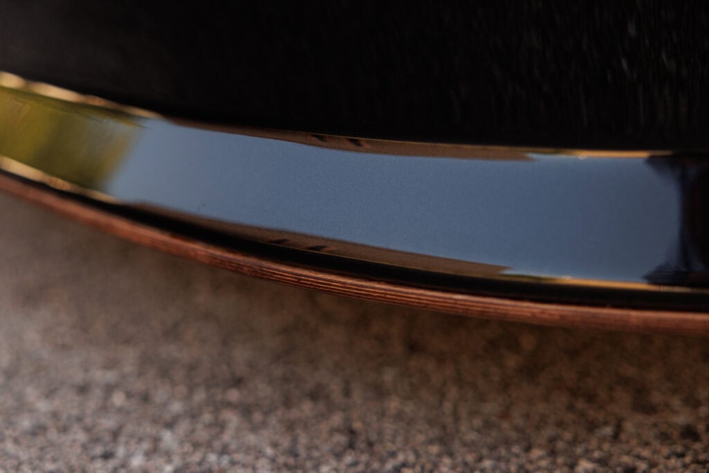 Close-up of the shiny black and copper bumper of a 1989 Porsche 964.