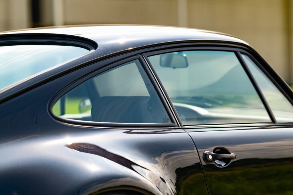 Close-up of a sleek black 1989 Porsche 964 with smooth curves and tinted windows.