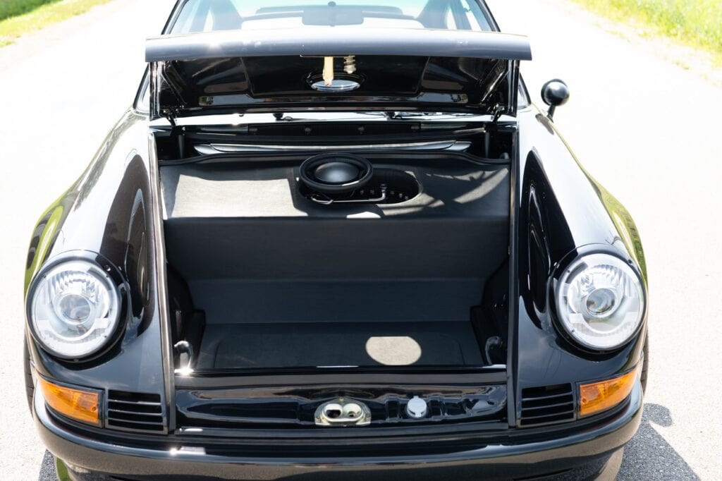 Classic 1989 Porsche 964 with open front trunk, black exterior, and round headlights.