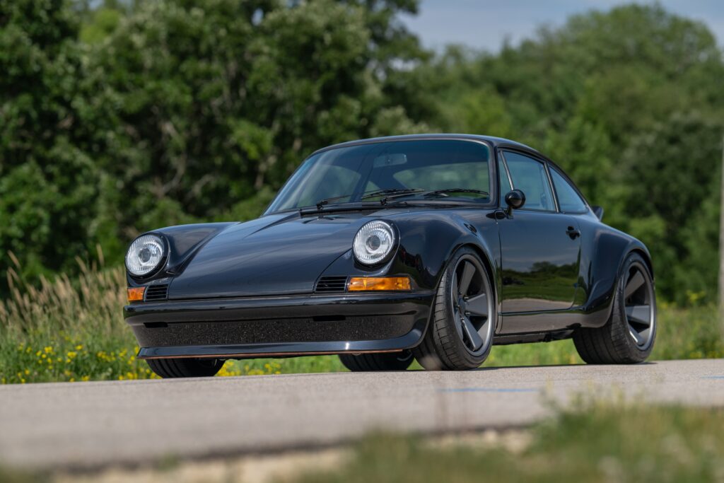 1989 Porsche 964 sports car parked outdoors with greenery background.