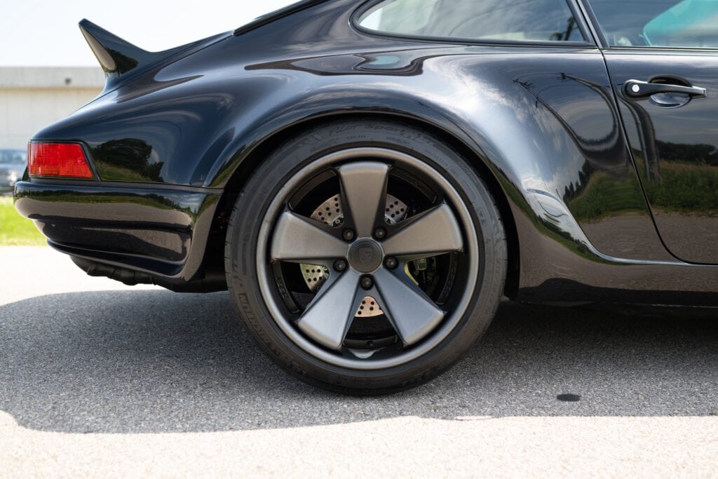 Close-up of black Porsche 964 rear wheel and fender.