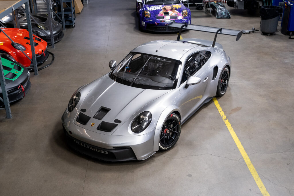 Silver Porsche 911 GT3 Cup 992 in garage with racing decals.