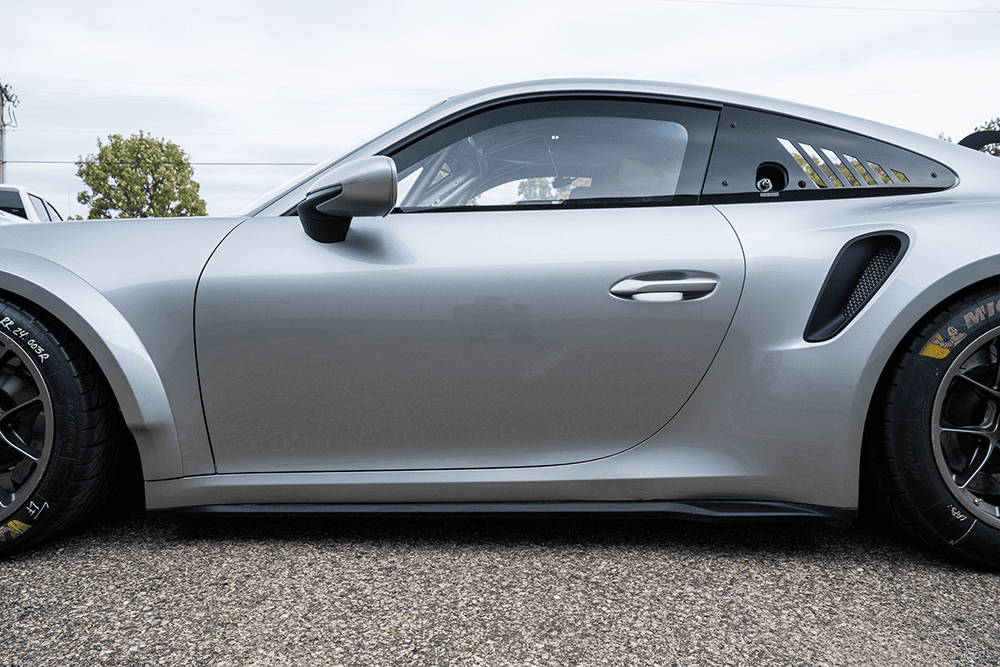 Silver Porsche 911 GT3 Cup 992 racing car parked outdoors.