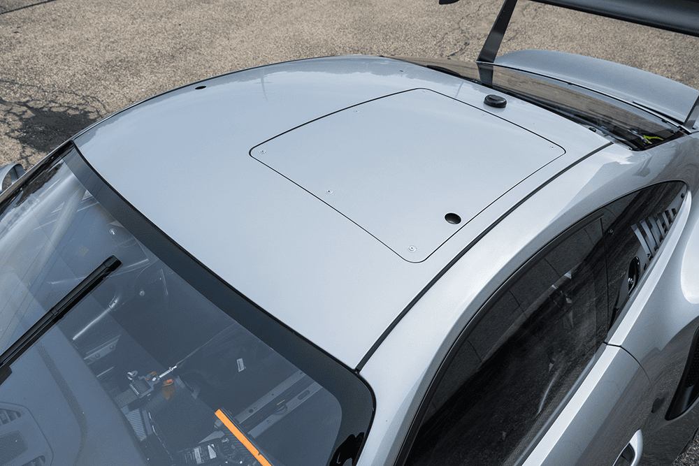 Close-up of the roof and rear wing of a silver Porsche 911 GT3 Cup 992 race car.