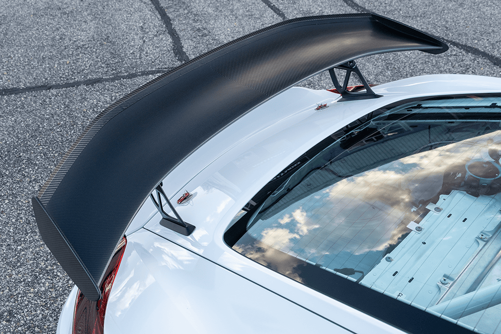 Close-up of a white Porsche 981 Clubsport MR with a large carbon fiber rear wing.