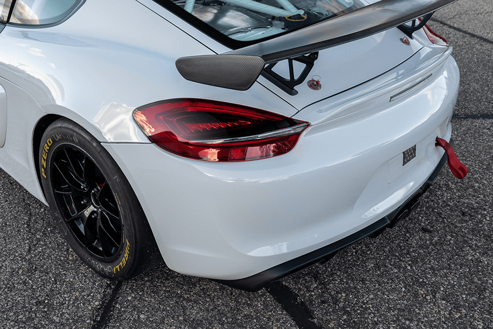 Close-up of a white Porsche 981 Clubsport MR rear with black wheels and spoiler.