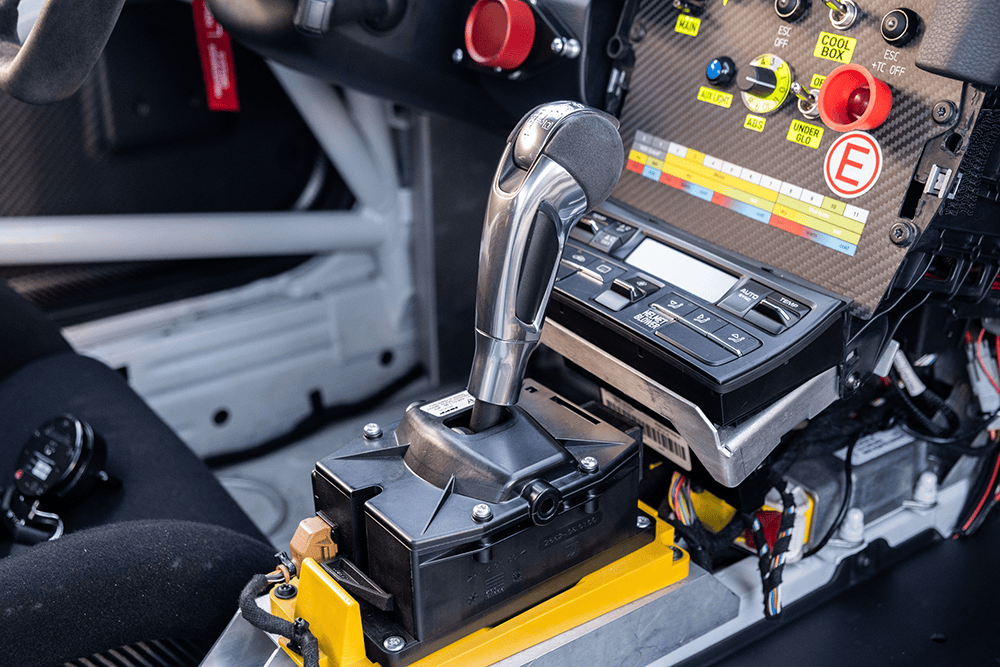 Race car gear shifter and dashboard controls in a high-performance vehicle.
