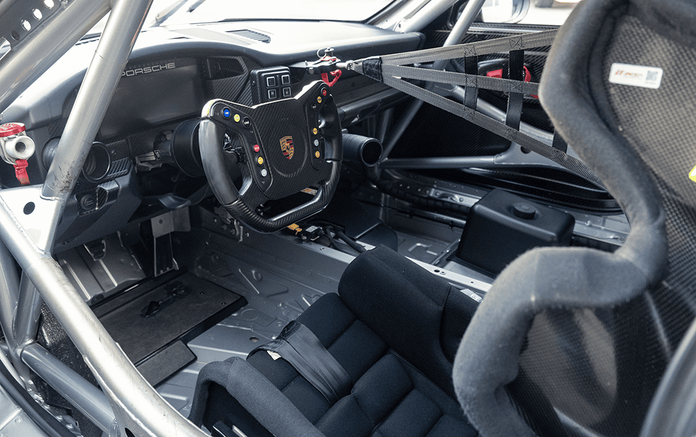 Racing car interior with steering wheel and safety harness.