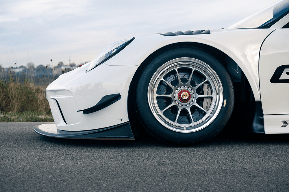 Close-up of a white Kellymoss GT4R race car wheel and front bumper.