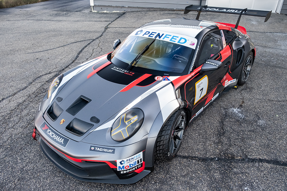 Kellymoss Porsche 911 GT3 Cup race car on track with sponsor decals.