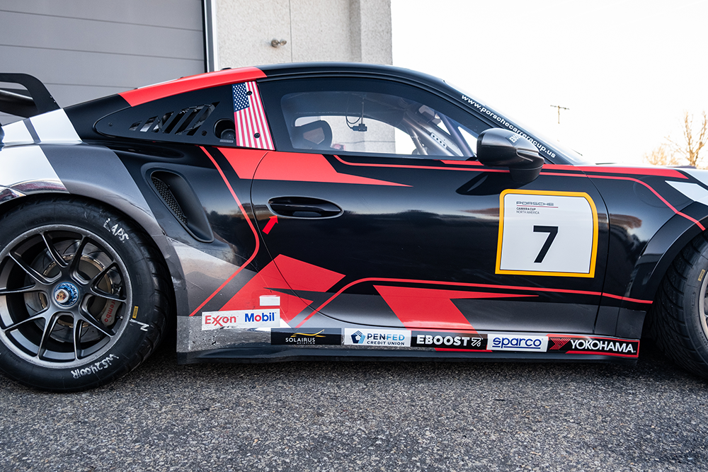 Black and red Porsche 911 GT3 Cup race car with number 7 and sponsor logos.