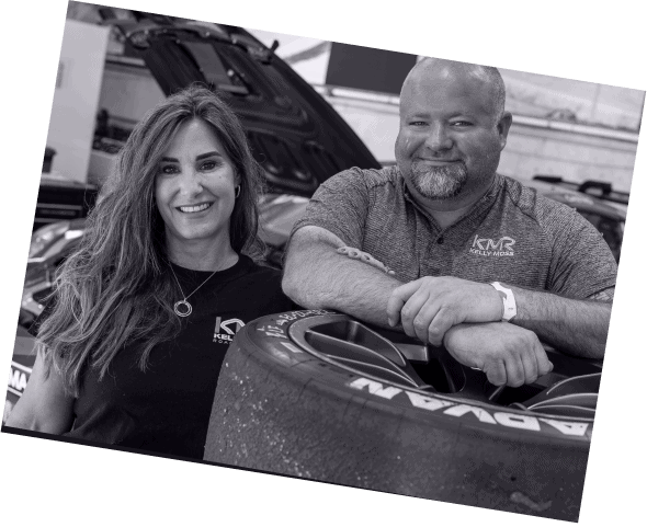 Kellymoss team members with race car in workshop setting.