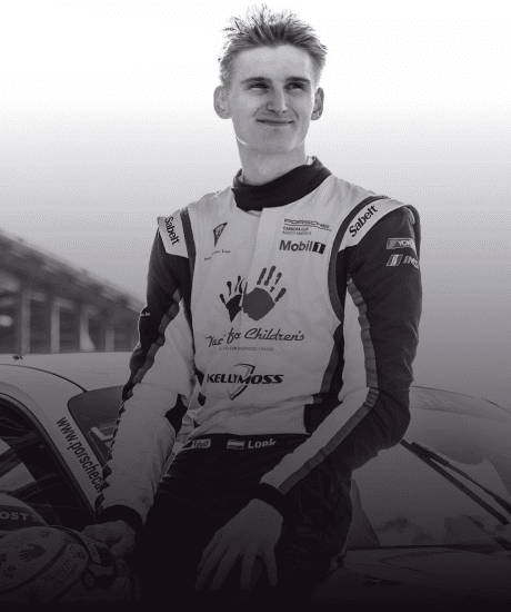Race car driver in racing suit standing next to a car at GT World Challenge America.
