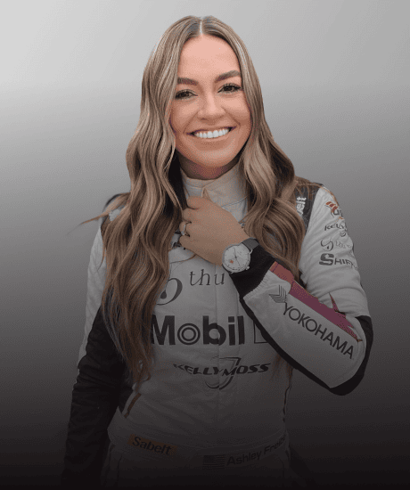 Kelly Moss racing driver in her racing suit smiling at the camera.