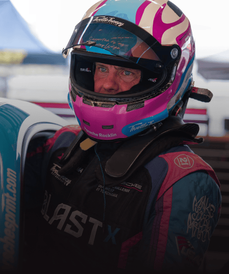 Porsche Carrera Cup driver in racing helmet and suit preparing for race.