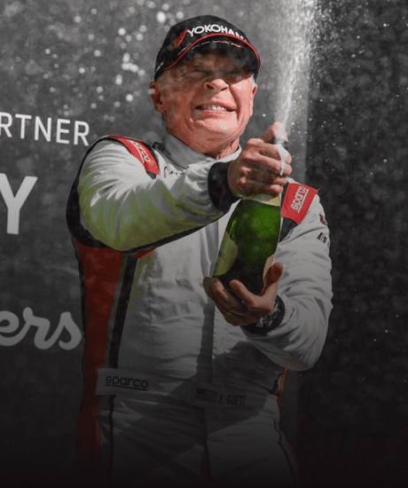 Race car driver celebrating with champagne at Porsche Carrera Cup North America.
