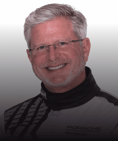 Portrait of a smiling man in Porsche Motorsport racing suit.
