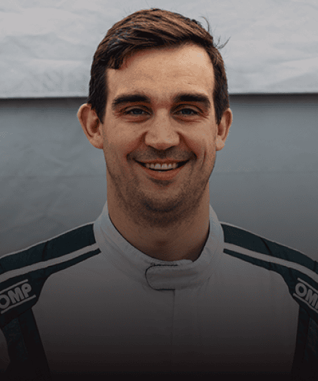 Portrait of a smiling race car driver in racing suit at Porsche Club event.