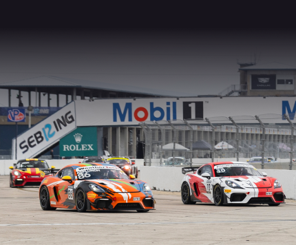 Race cars on track at Kellymoss motorsport event with sponsor banners.