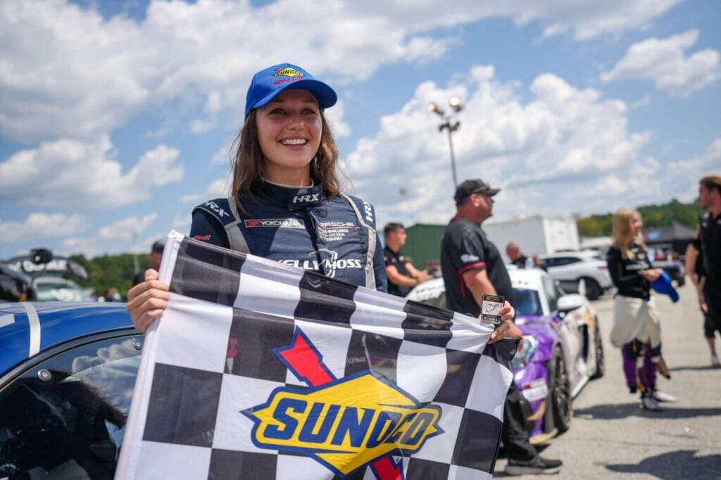 Kellymoss driver holding checkered flag and smiling at Road Atlanta race.