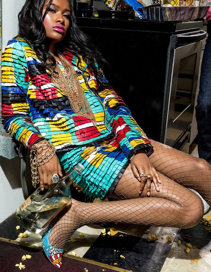 Fashion model in colorful outfit sitting on kitchen floor with fishnet stockings.