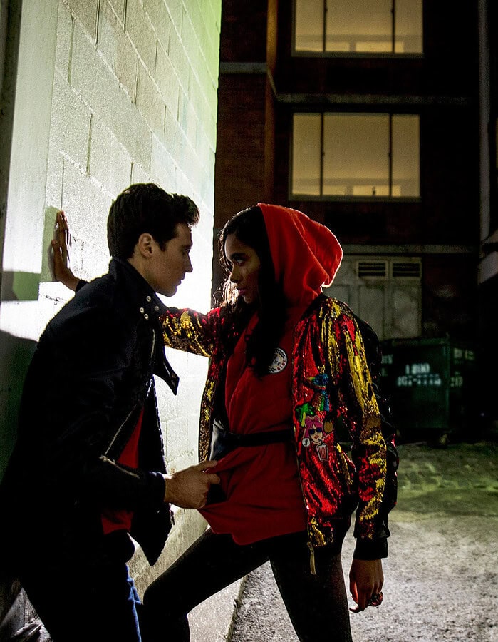 Two young people in an urban alleyway at night, engaging in a dramatic pose.