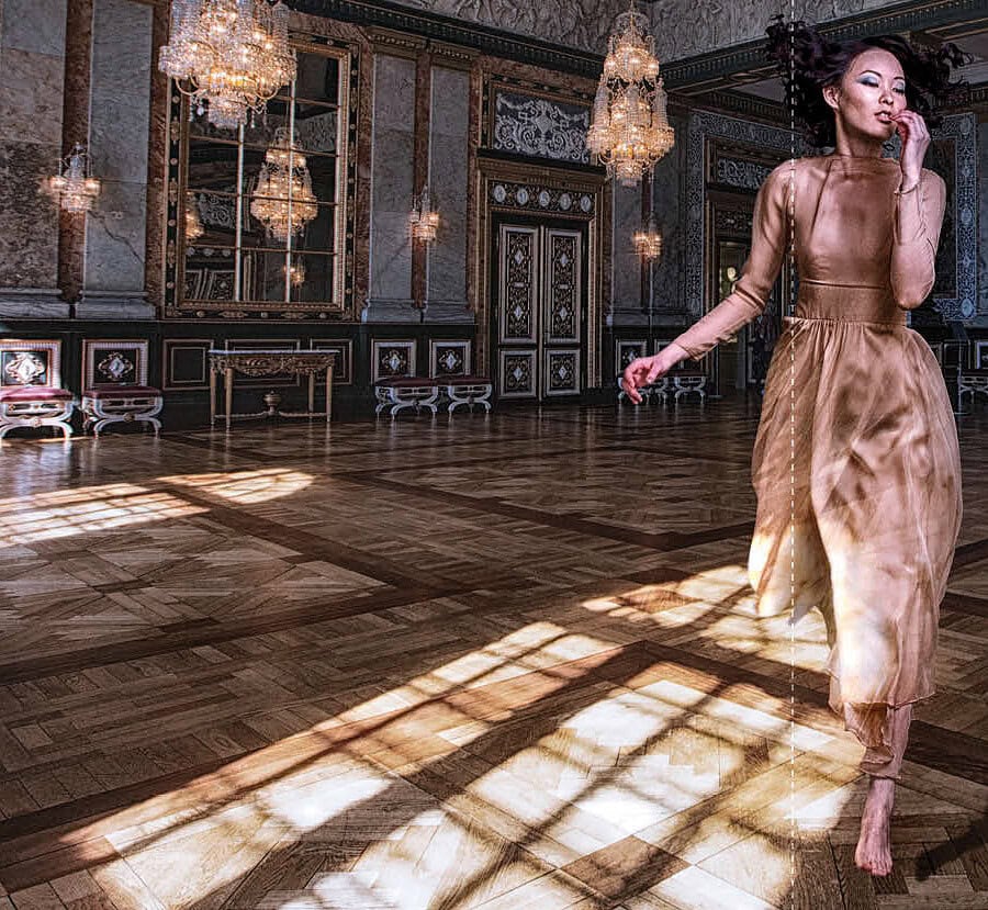 Elegant woman in a gold dress dancing in a luxurious ballroom with chandeliers. photographer NYC