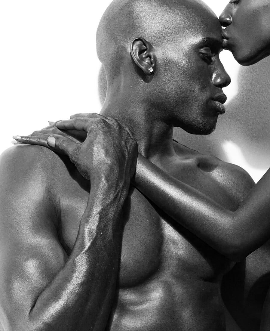 Closely cropped black-and-white portrait of two models holding one another.