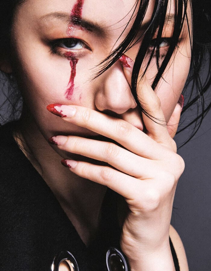 Close-up of a woman with makeup and tears on her face, covering her mouth with her hand. photographer NYC