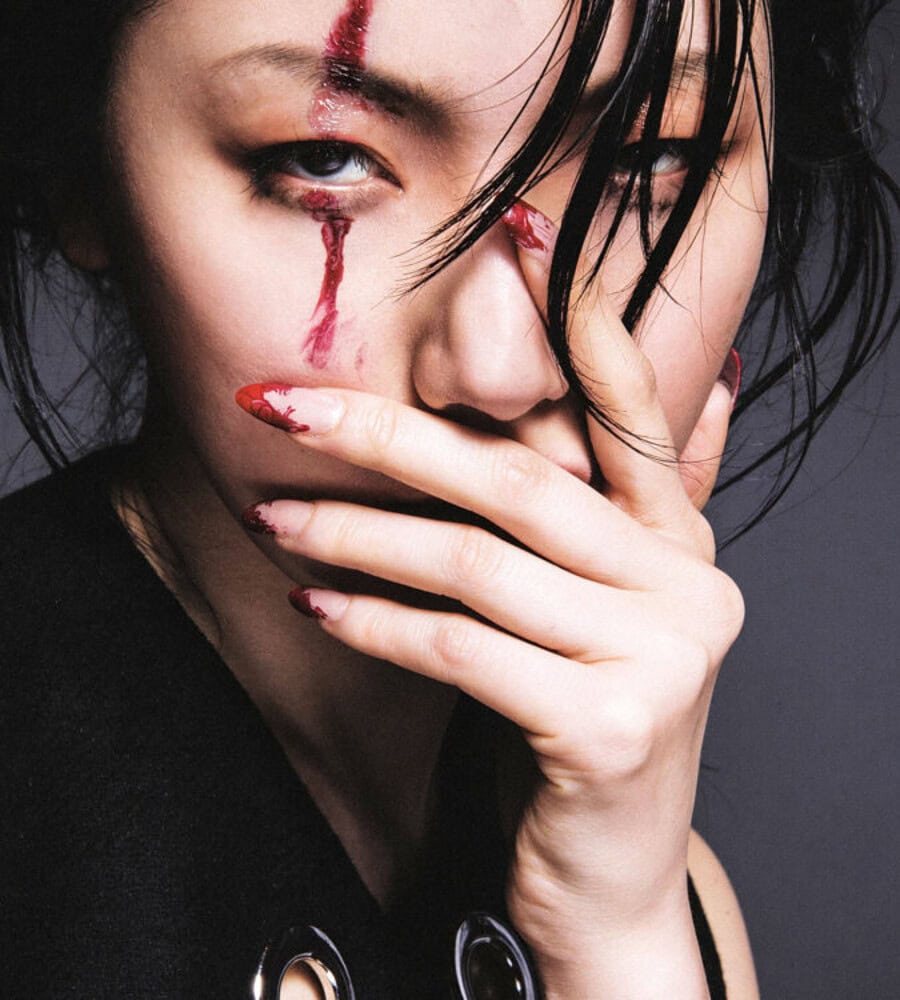 Close-up of a woman with makeup and tears on her face, covering her mouth with her hand. photographer NYC